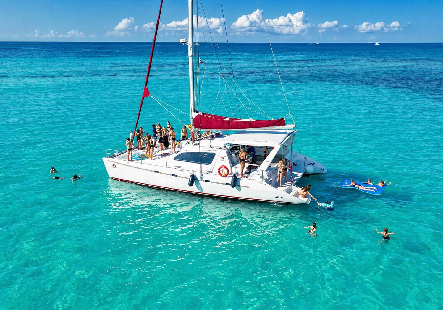 Swimmers in clear Caribbean water alongside the catamaran